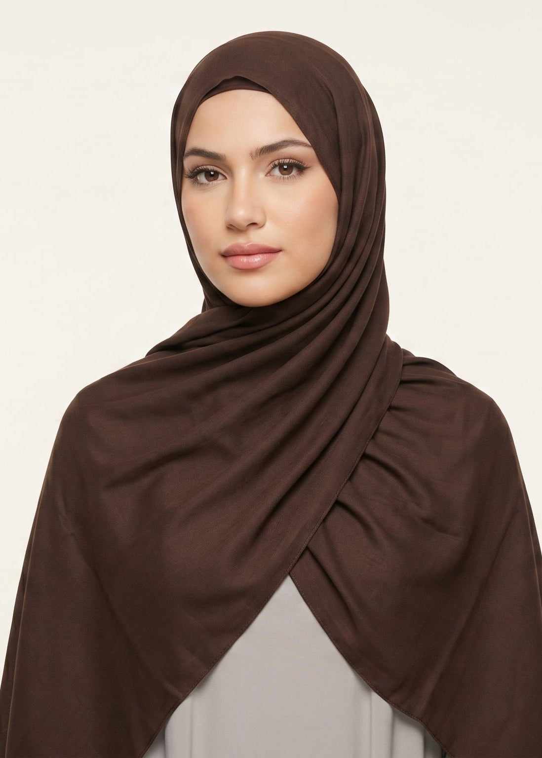 Woman wearing a brown hijab against a beige background