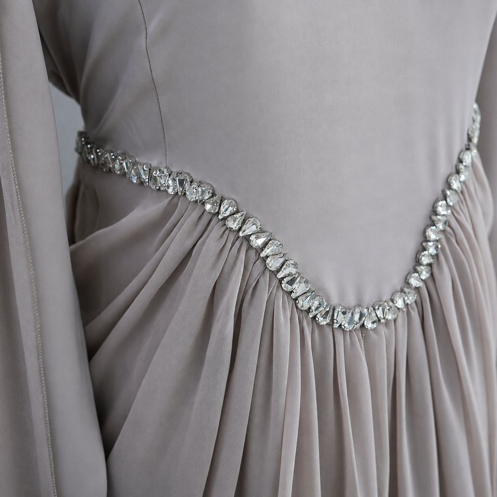 Close-up of a draped taupe-gray evening gown with a sparkling silver rhinestone waistband.