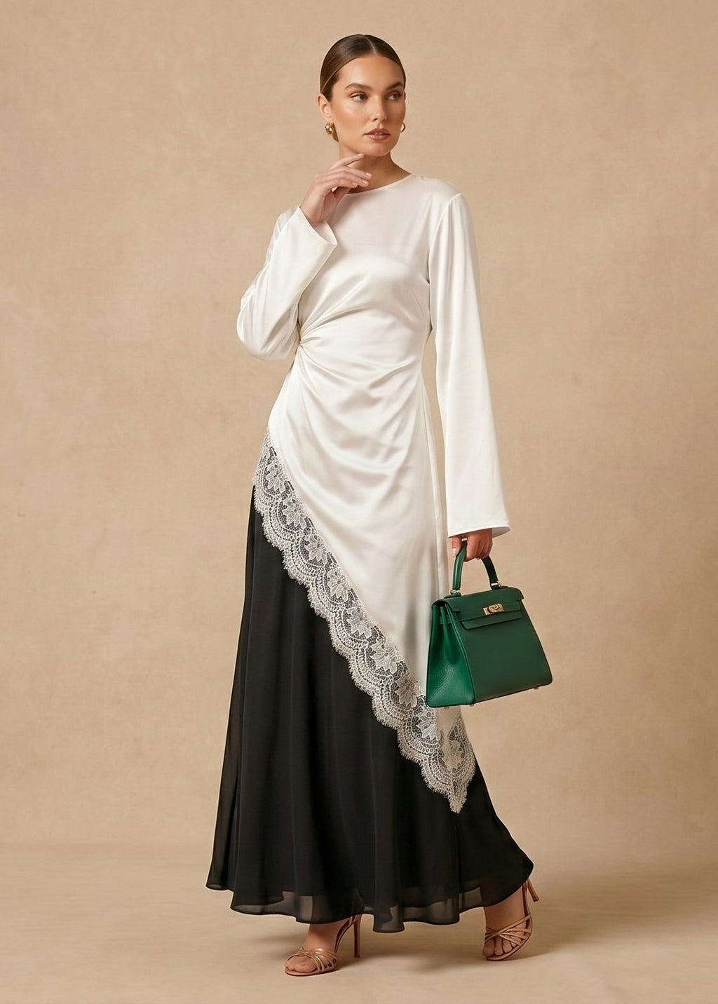 Woman wearing a white and black saree holding a green handbag against a beige background