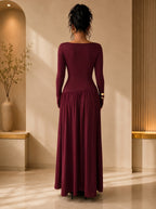 Woman wearing a burgundy long-sleeve dress standing in a softly lit room.
