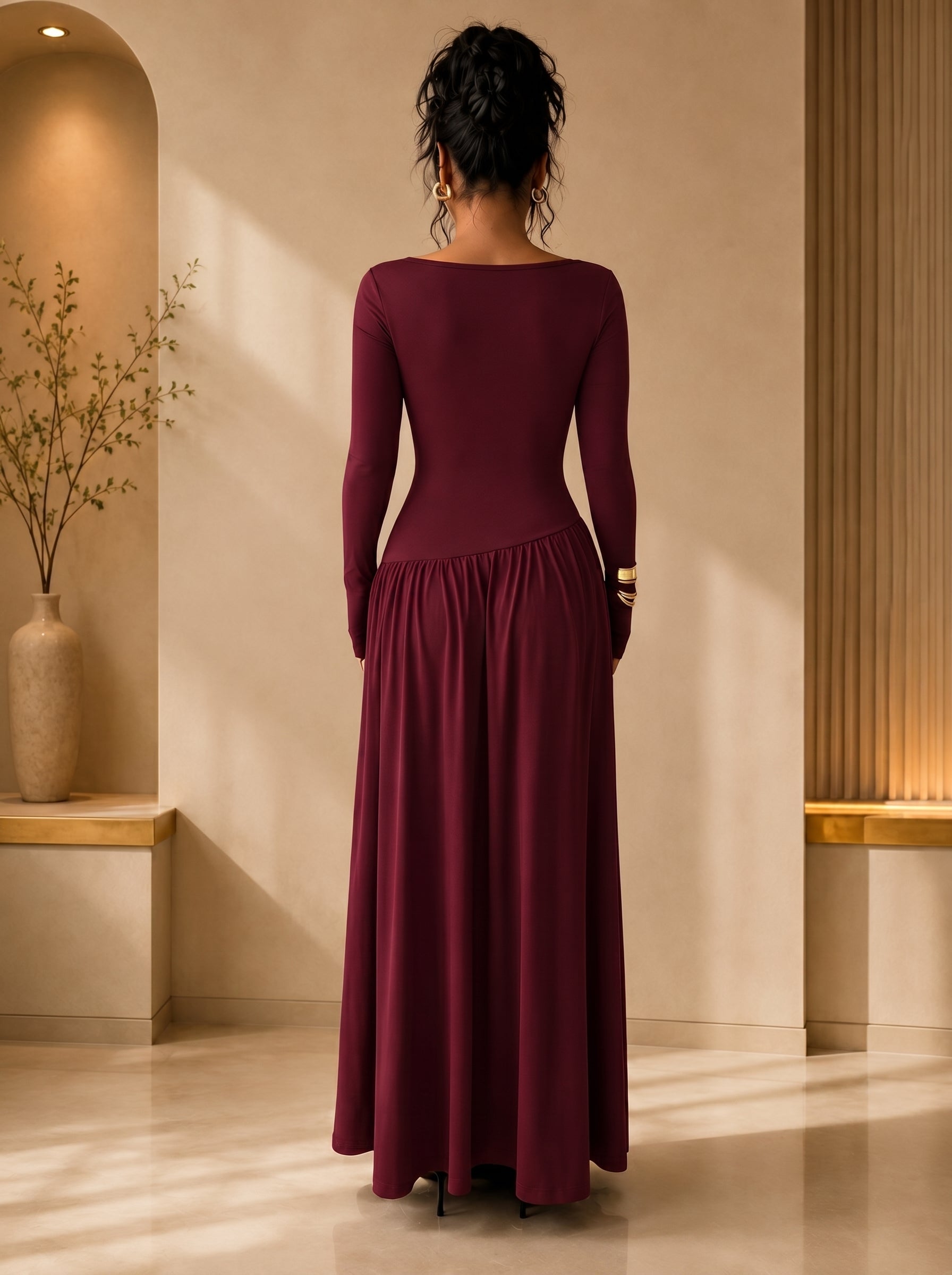 Woman wearing a burgundy long-sleeve dress standing in a softly lit room.