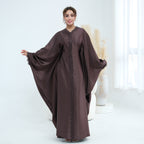Woman wearing a brown abaya in a white room
