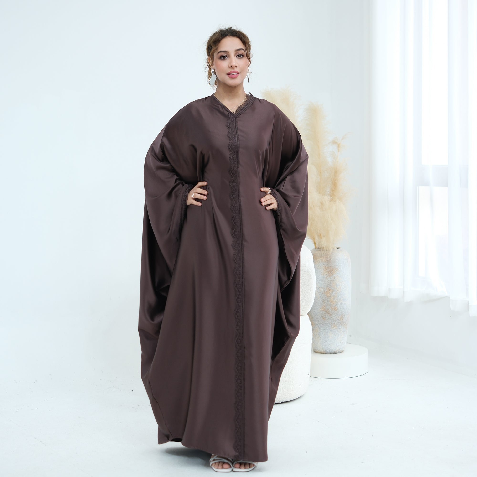 Woman wearing a brown abaya in a white room