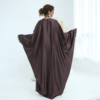 Woman wearing a brown abaya in a white room