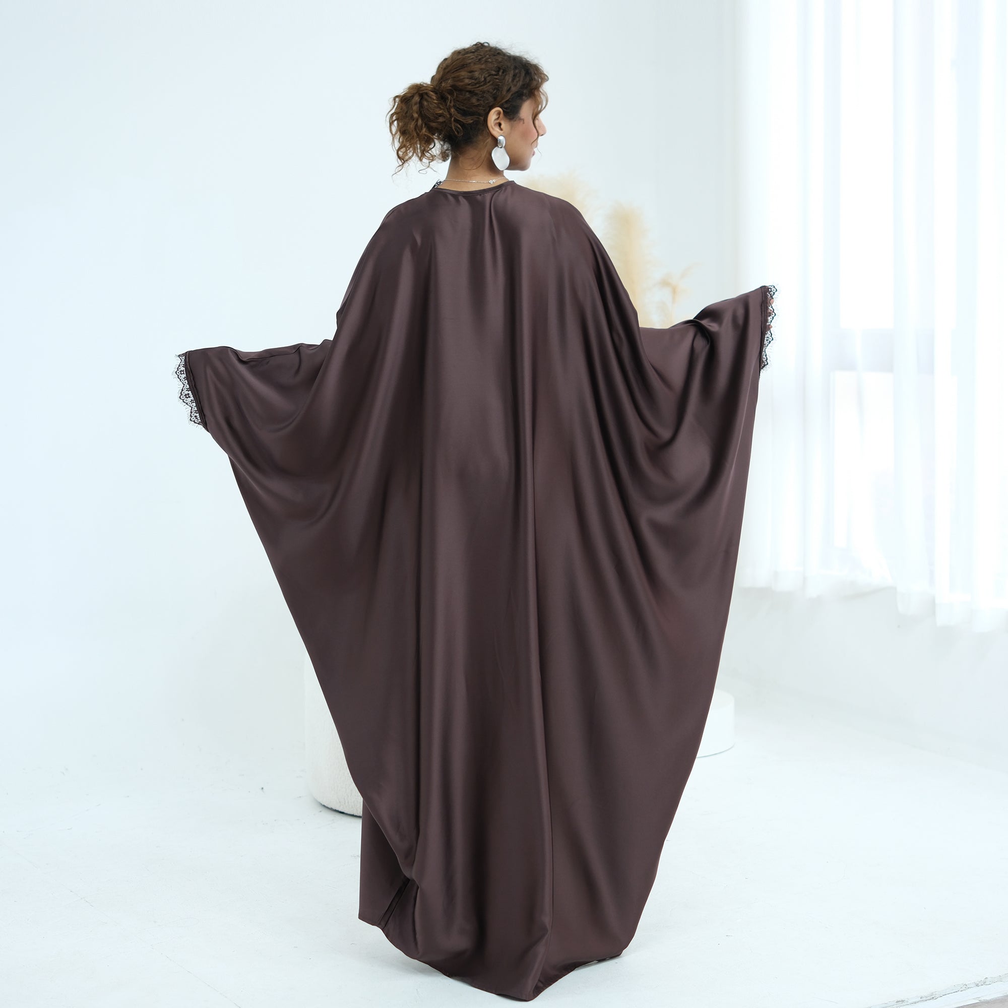 Woman wearing a brown abaya in a white room