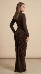 Woman wearing a brown long-sleeve dress with a draped effect on a beige background