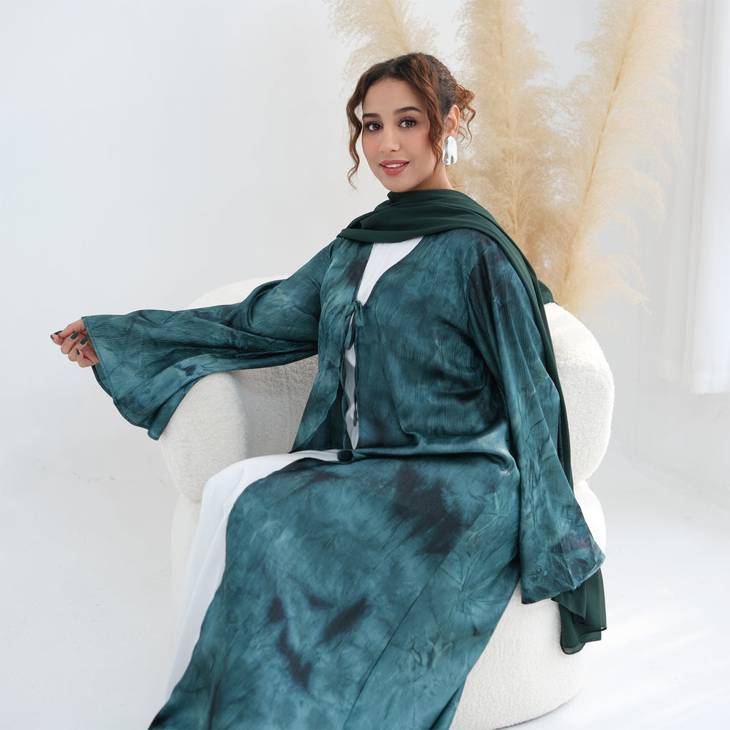 Woman wearing a green dress with a matching scarf sitting on a white chair.