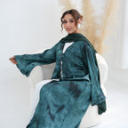 Woman wearing a green dress with a matching scarf sitting on a white chair.