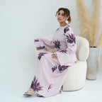 Woman in a pink floral dress sitting on a white chair with a neutral background