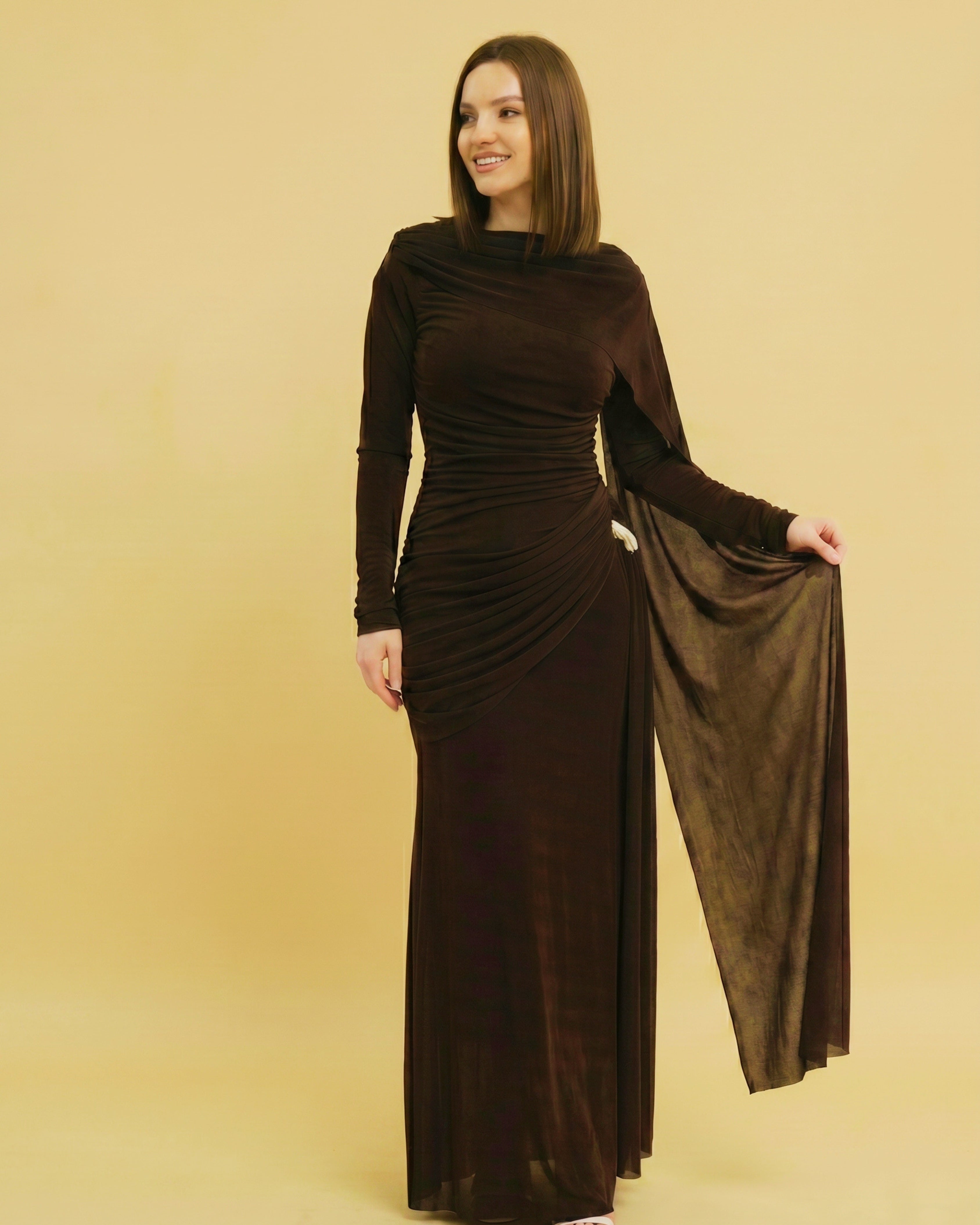 Woman wearing a brown evening gown against a beige background