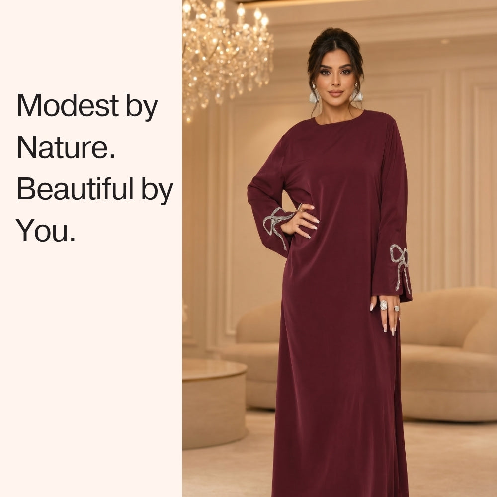 Woman in a burgundy dress with decorative sleeves in an elegant room.