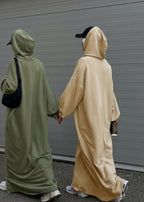 Two people wearing long, hooded cloaks walking side by side on a street.
