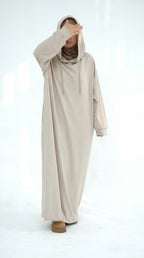 Person wearing a long beige hoodie on a white background