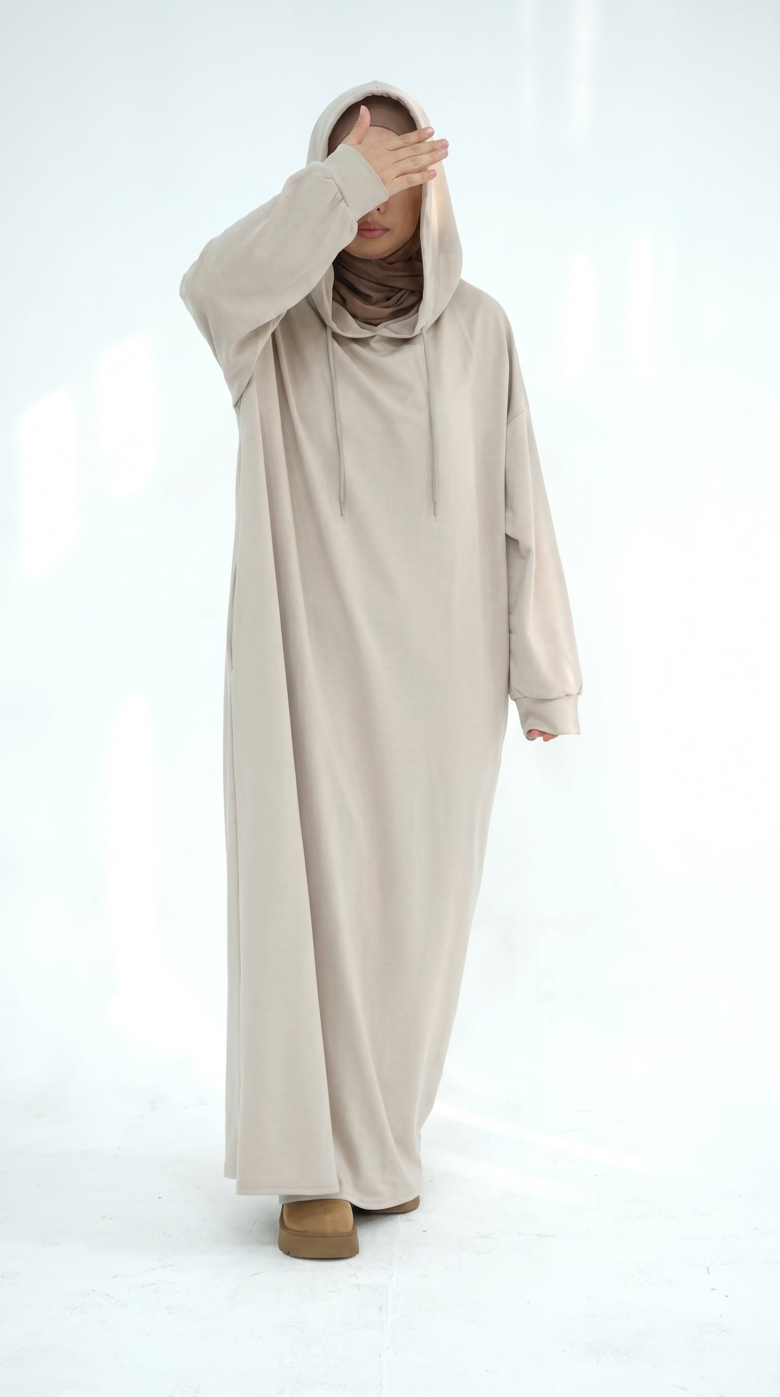 Person wearing a long beige hoodie on a white background