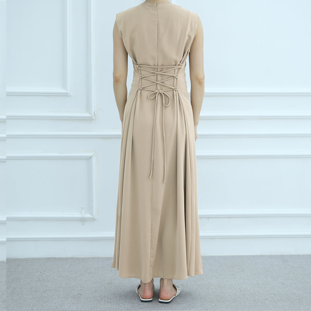 Beige long dress on a mannequin against a white paneled wall.
