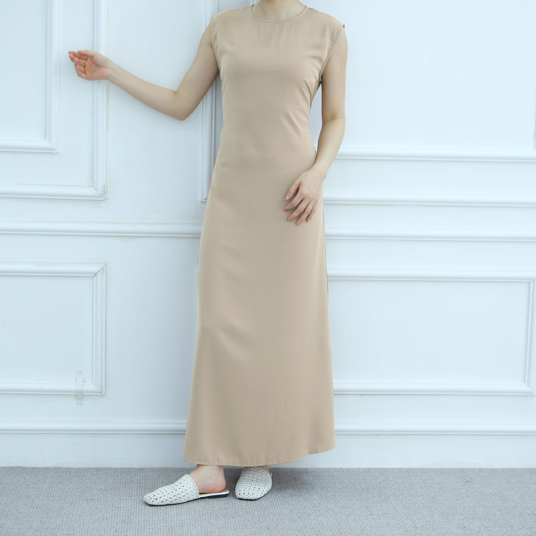 Beige dress worn by a person against a white paneled wall.