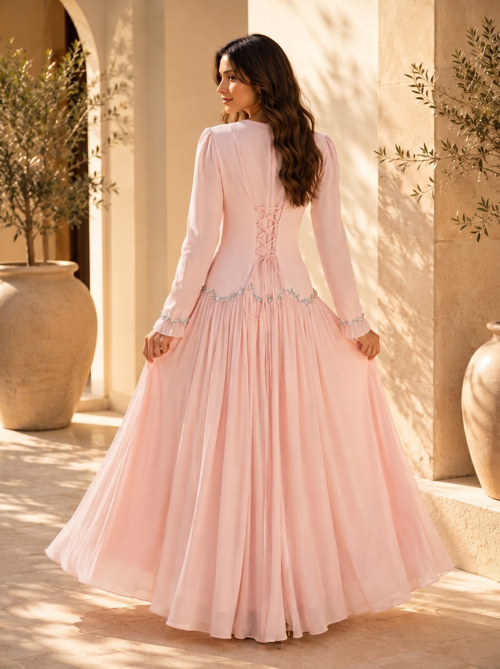 Woman in a pink dress standing in a sunlit outdoor setting with architectural elements.