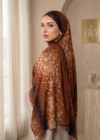 Woman wearing a patterned hijab in a room with neutral decor