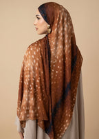 Woman wearing a brown patterned hijab against a beige background