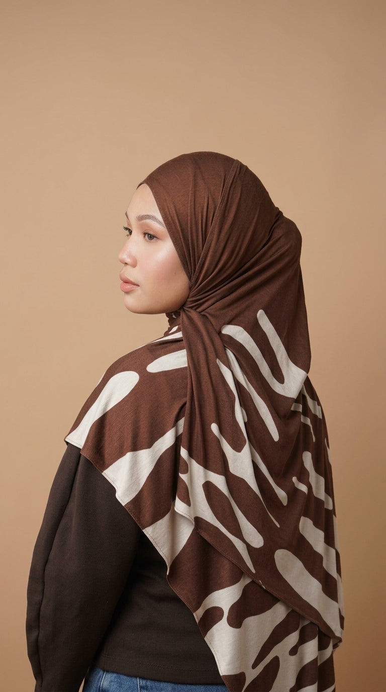 Woman wearing a brown and white patterned hijab against a beige background