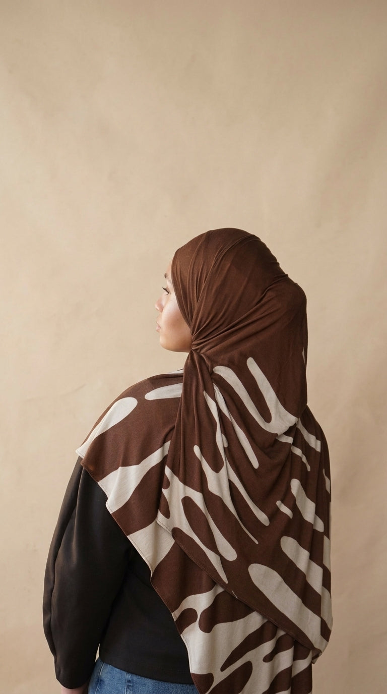 Person wearing a brown and beige patterned headscarf against a beige background