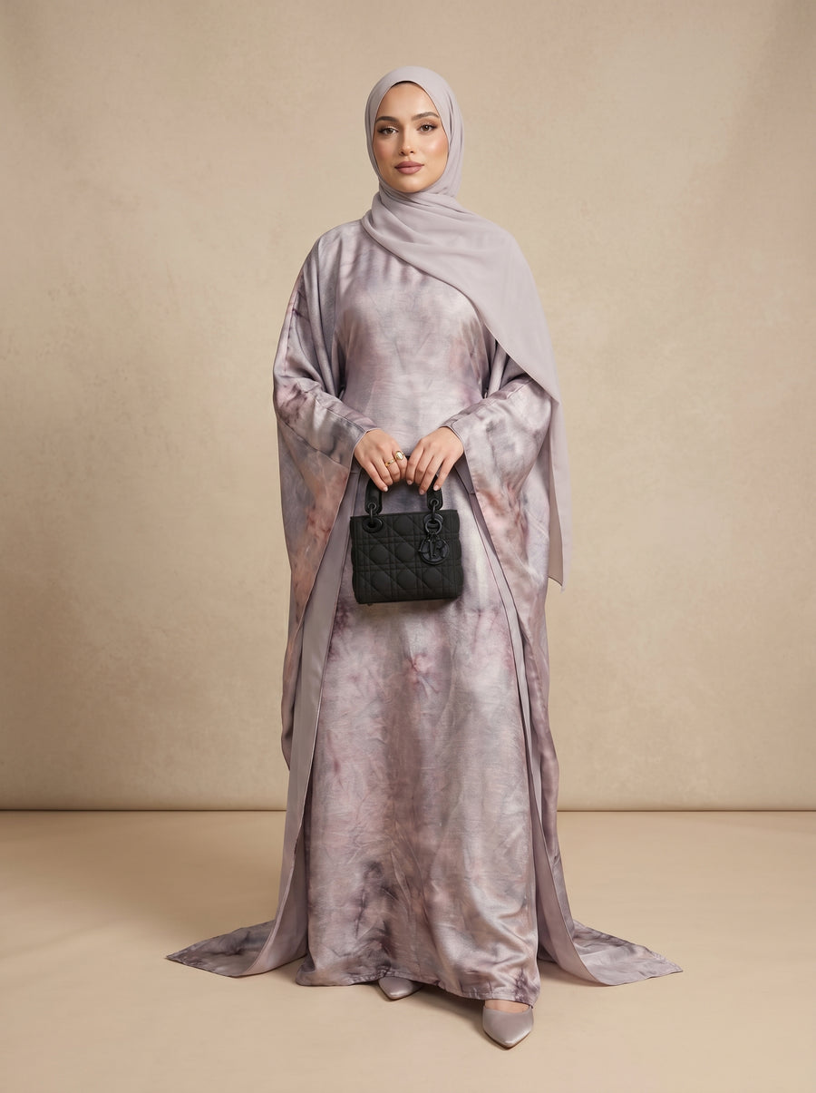 Woman wearing a long, light-colored dress with a matching hijab against a beige background