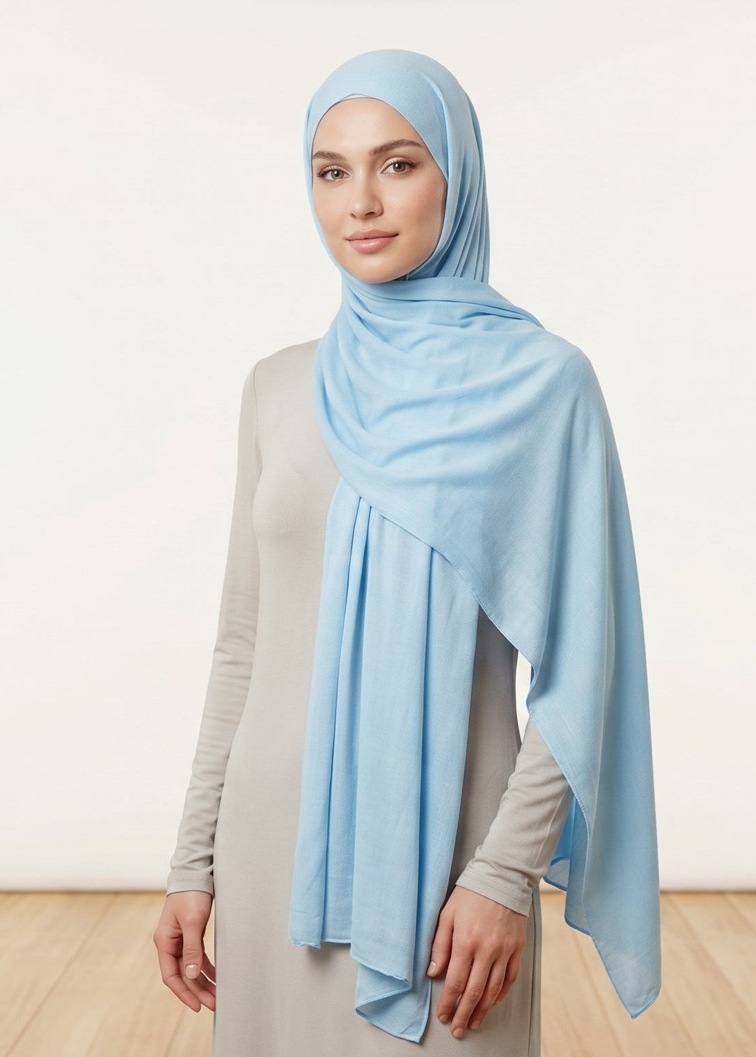 Woman wearing a light blue hijab against a white background