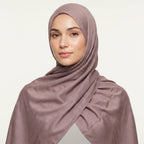 Woman wearing a mauve hijab against a light background