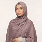 Woman wearing a mauve hijab against a plain background