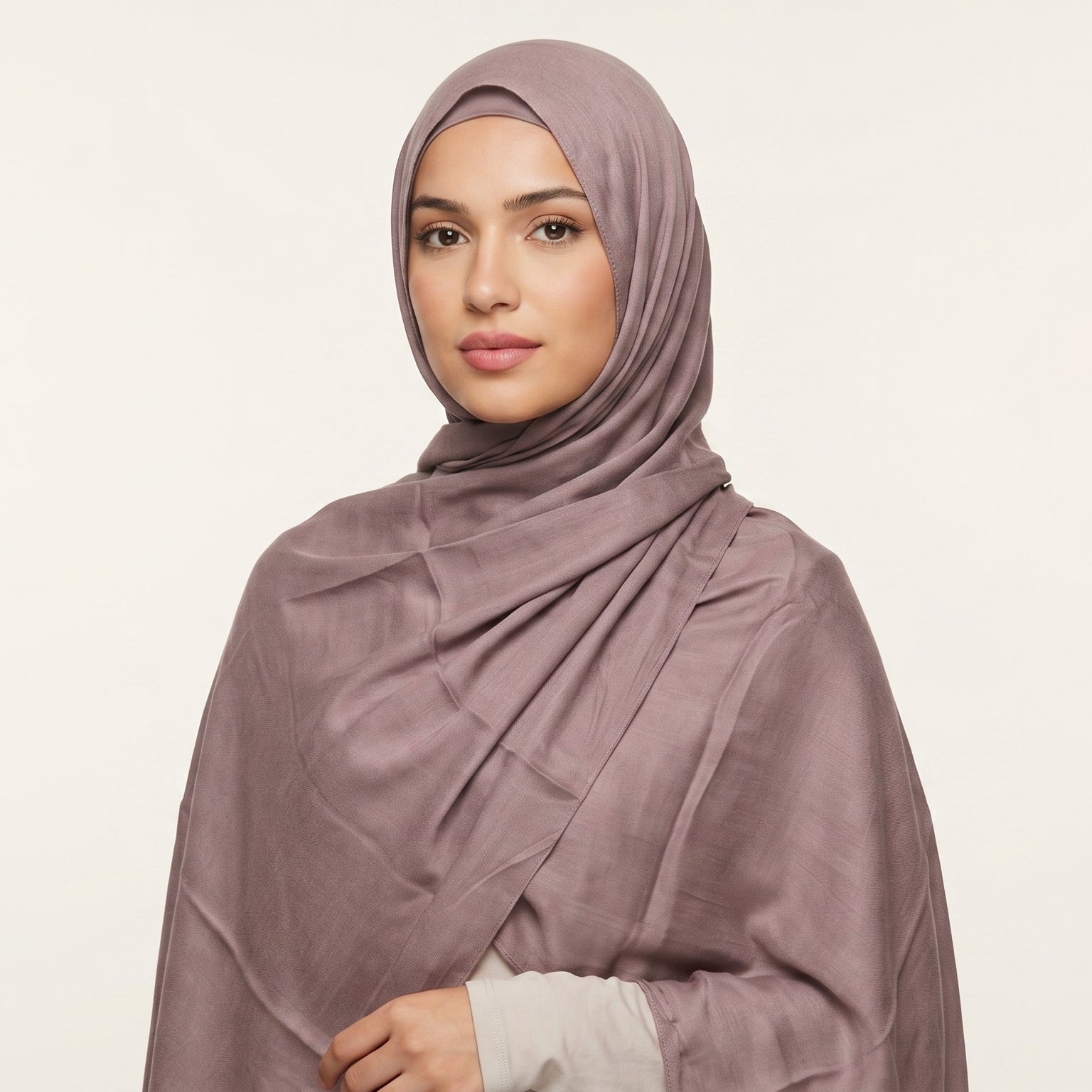 Woman wearing a mauve hijab against a plain background