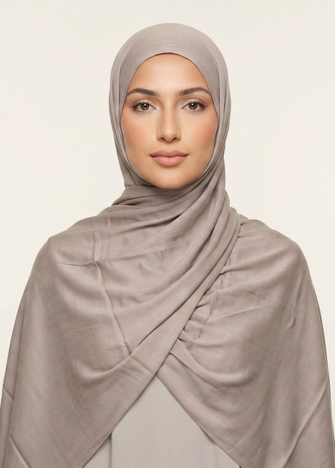 Woman wearing a beige hijab against a light background