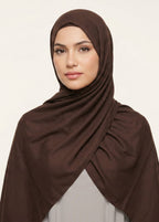 Woman wearing a brown hijab against a beige background