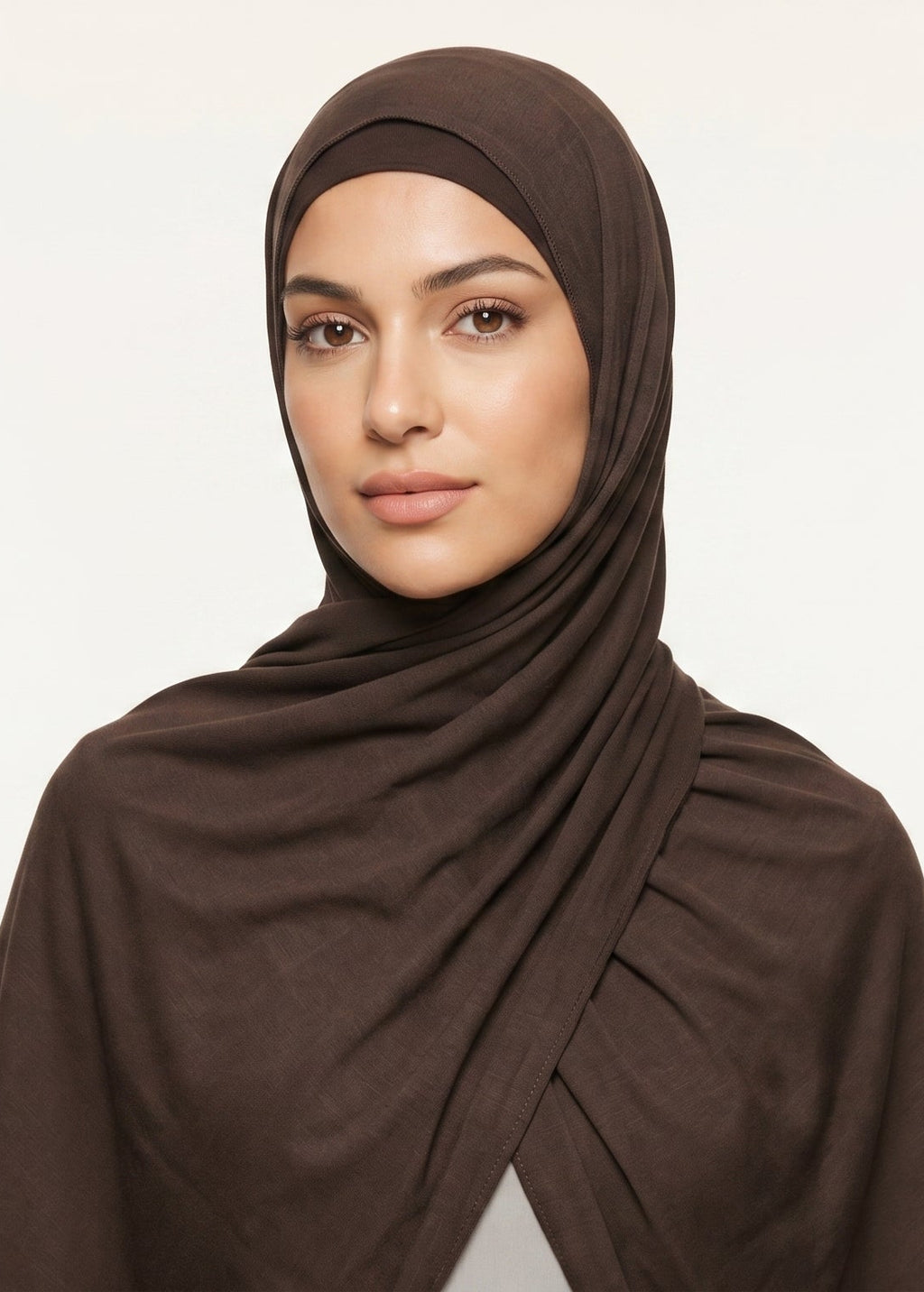 Woman wearing a brown hijab against a beige background