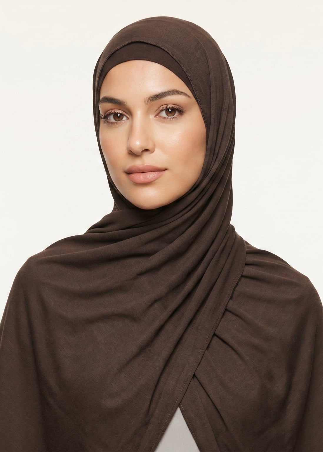 Woman wearing a brown hijab against a beige background