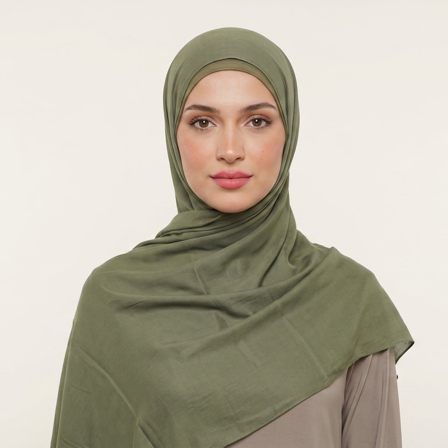 Woman wearing a green hijab against a plain background