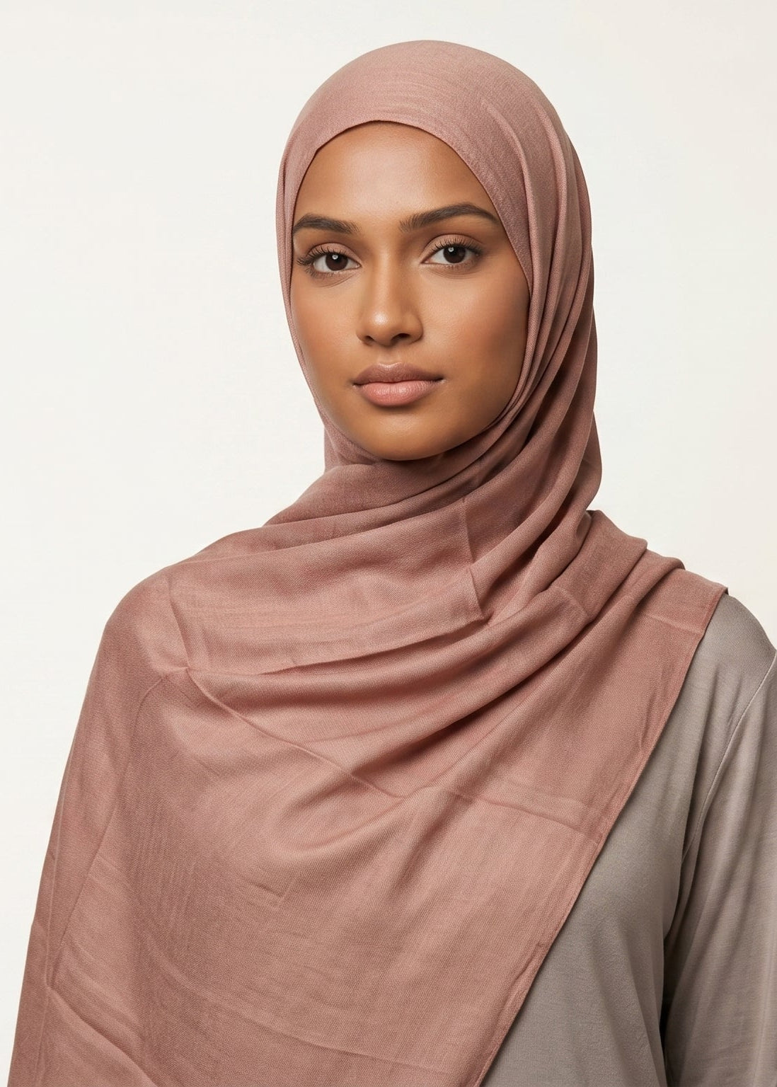 Woman wearing a pink hijab against a plain background