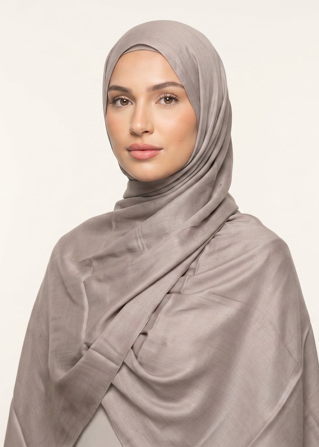 Woman wearing a beige hijab against a plain background