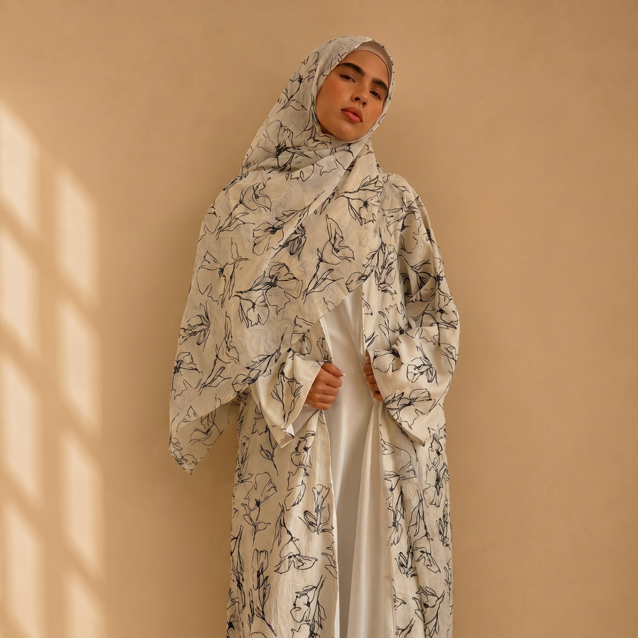 Woman wearing a floral abaya against a beige background