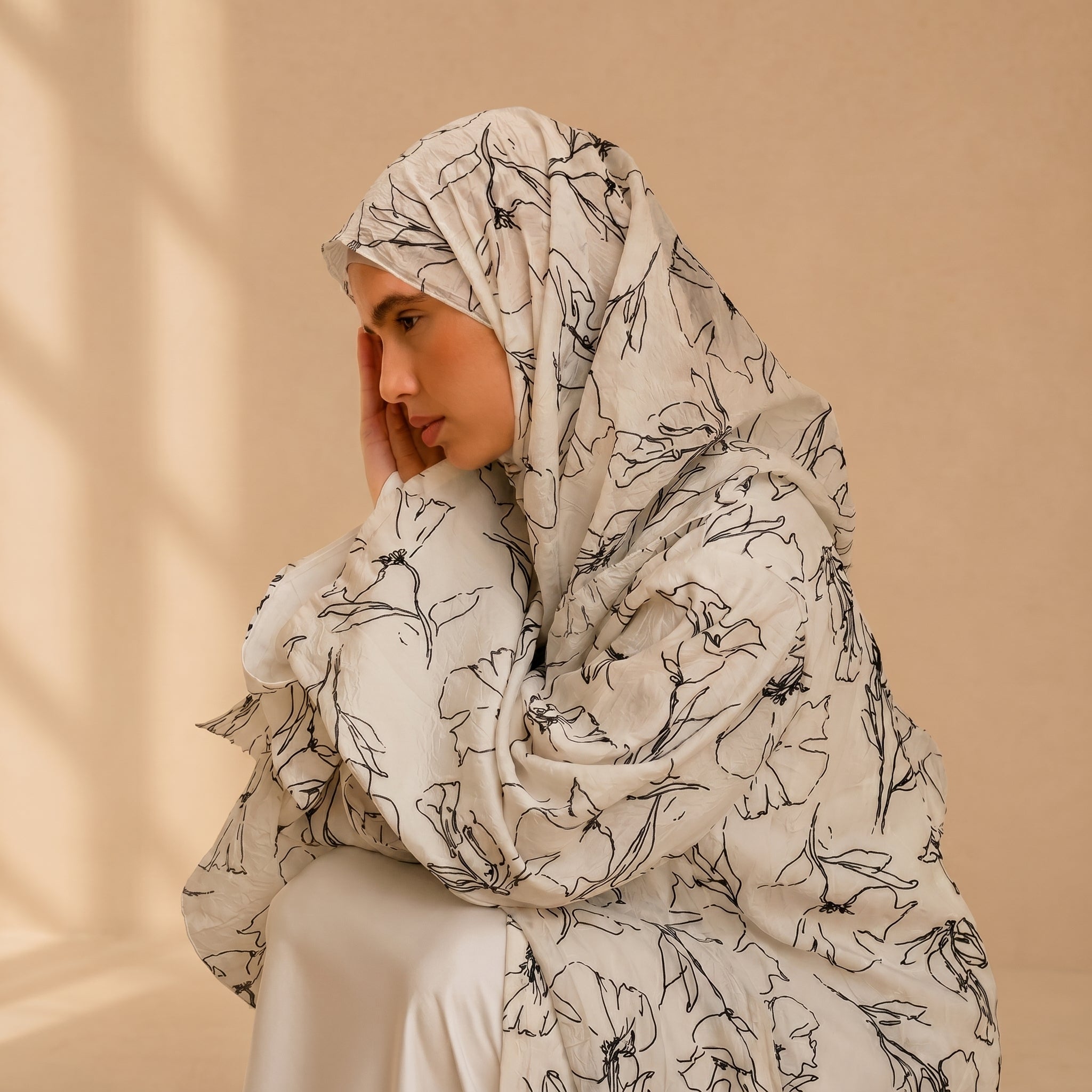 Woman wearing a floral hijab against a beige background